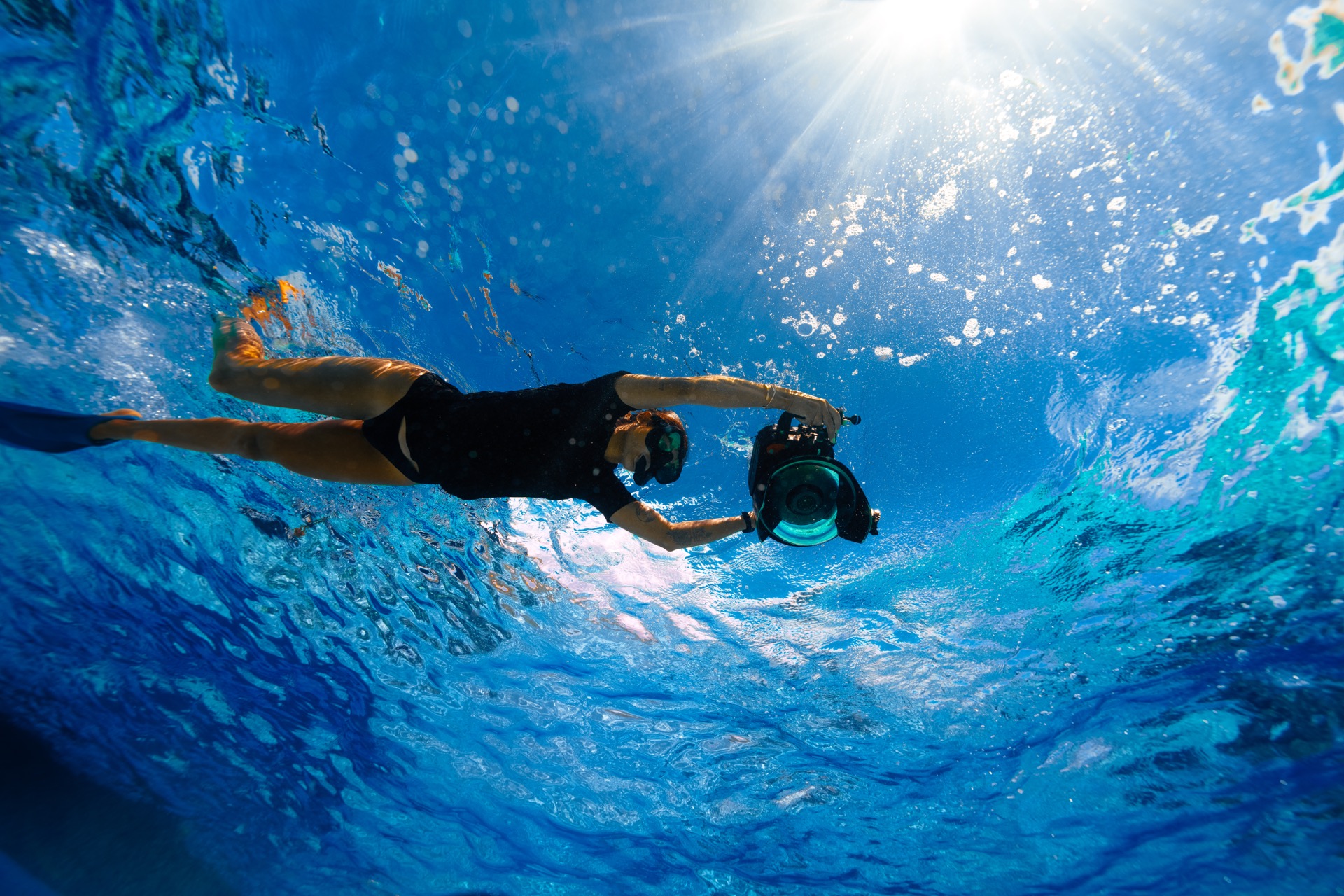 A freediver filming underwater with a camera in a housing