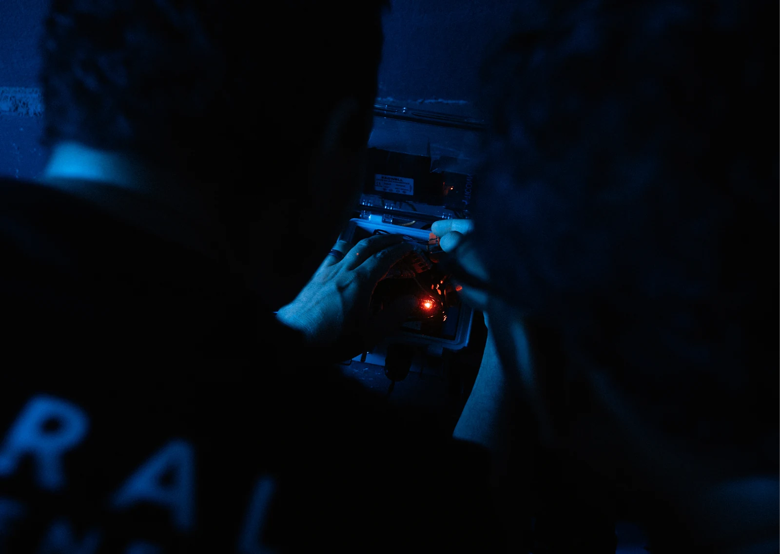An engineer soldering a circuit board by torchlight, lit blue