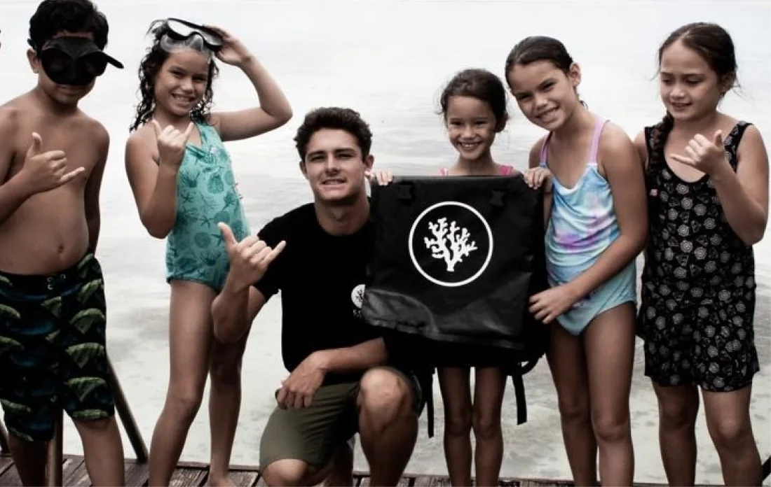 Island kids on the beach holding a Coral Gardeners flag
