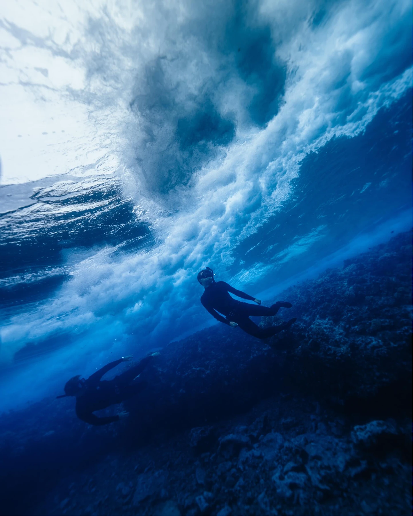 A freediver under a breaking wave over the reef
