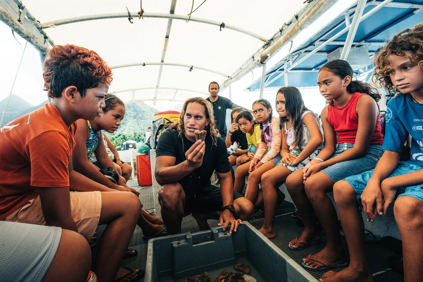 Children listening to a Coral Gardener on a boat