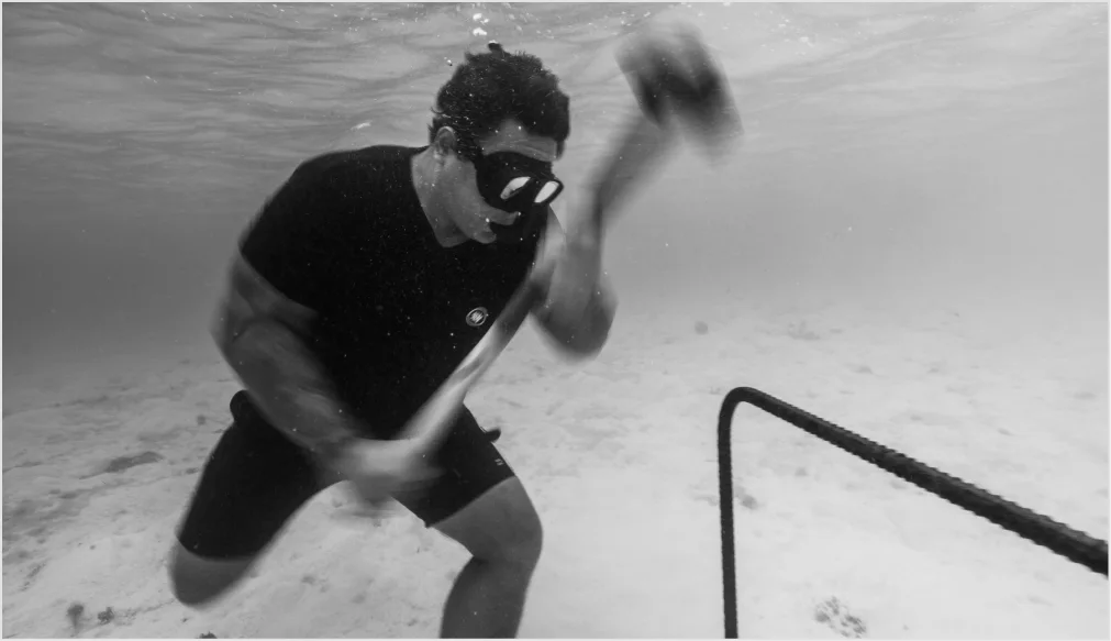 A Gardener hammering a nursery frame into the sand, in black and white