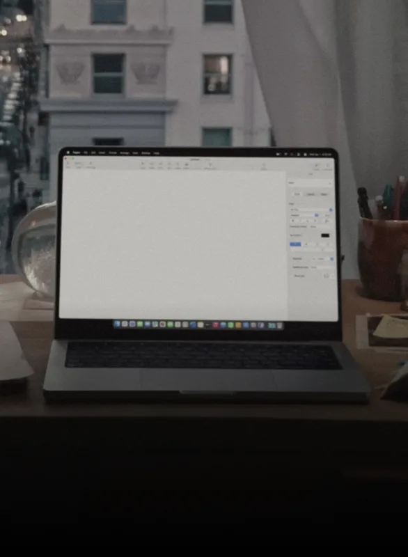 A MacBook open on a desk at dusk
